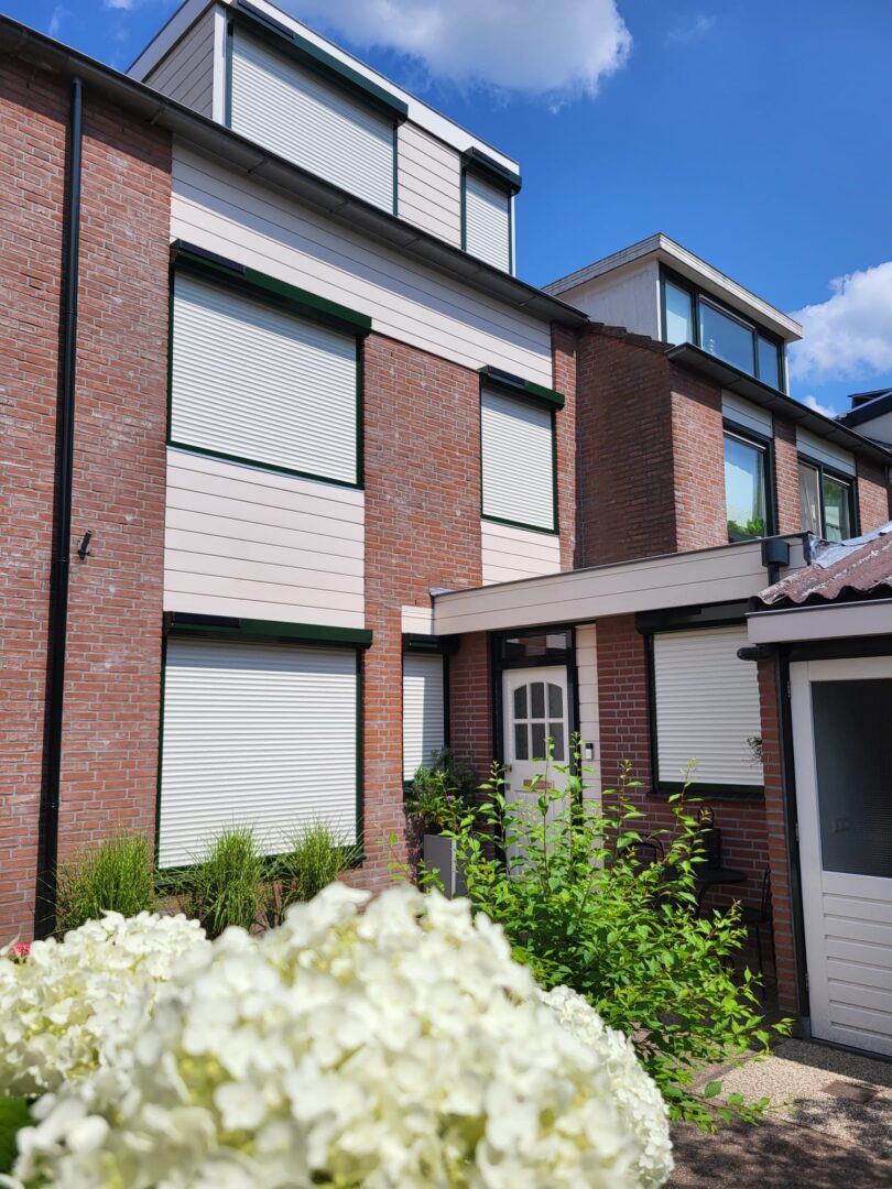 witte solar rolluiken met zwarte kast aan de voorkant van een woning